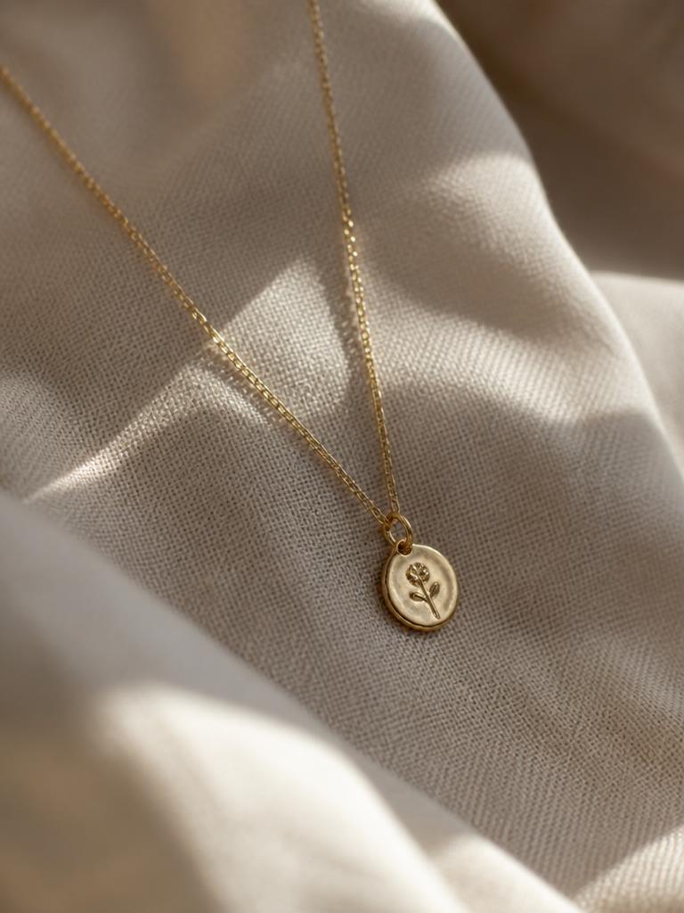 Dije pequeno de oro con cadena fina sobre tela de lino crema