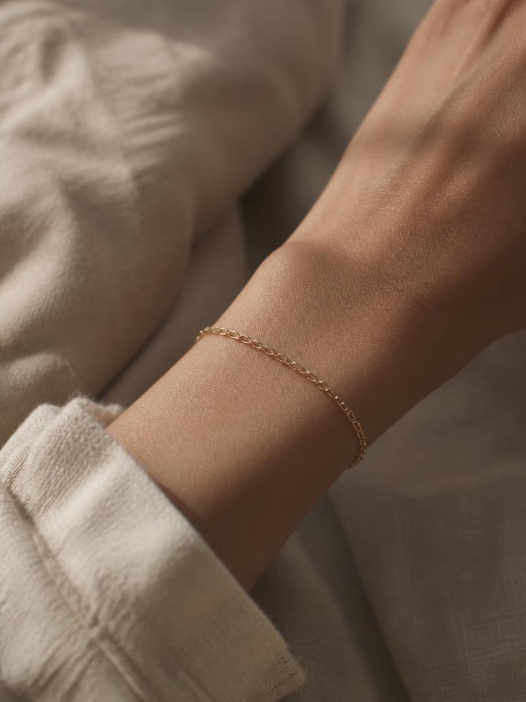 Pulsera de cadena fina de oro en la muneca, fondo de lino claro