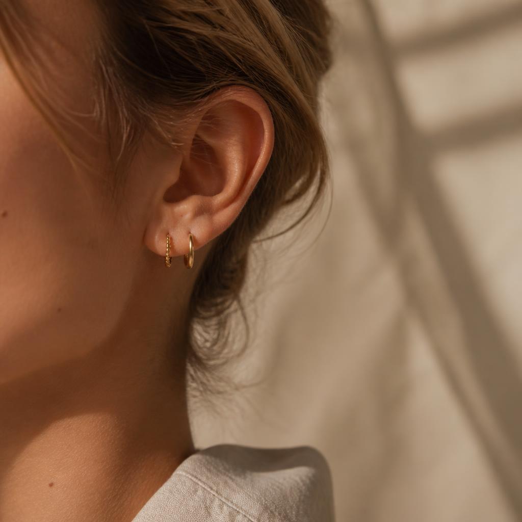 Detalle de oreja con arracadas pequeñas de oro