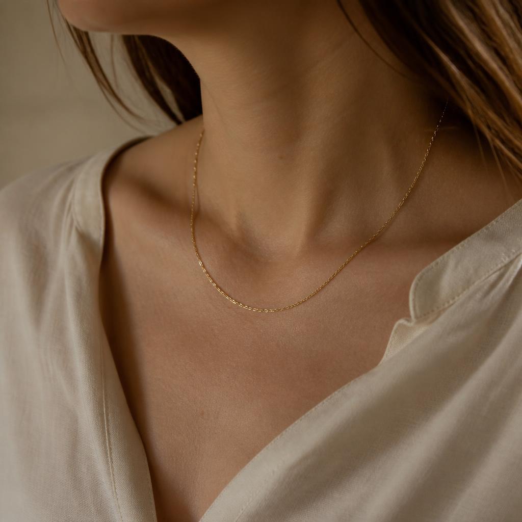 Cadena fina de oro sobre cuello con blusa color crema